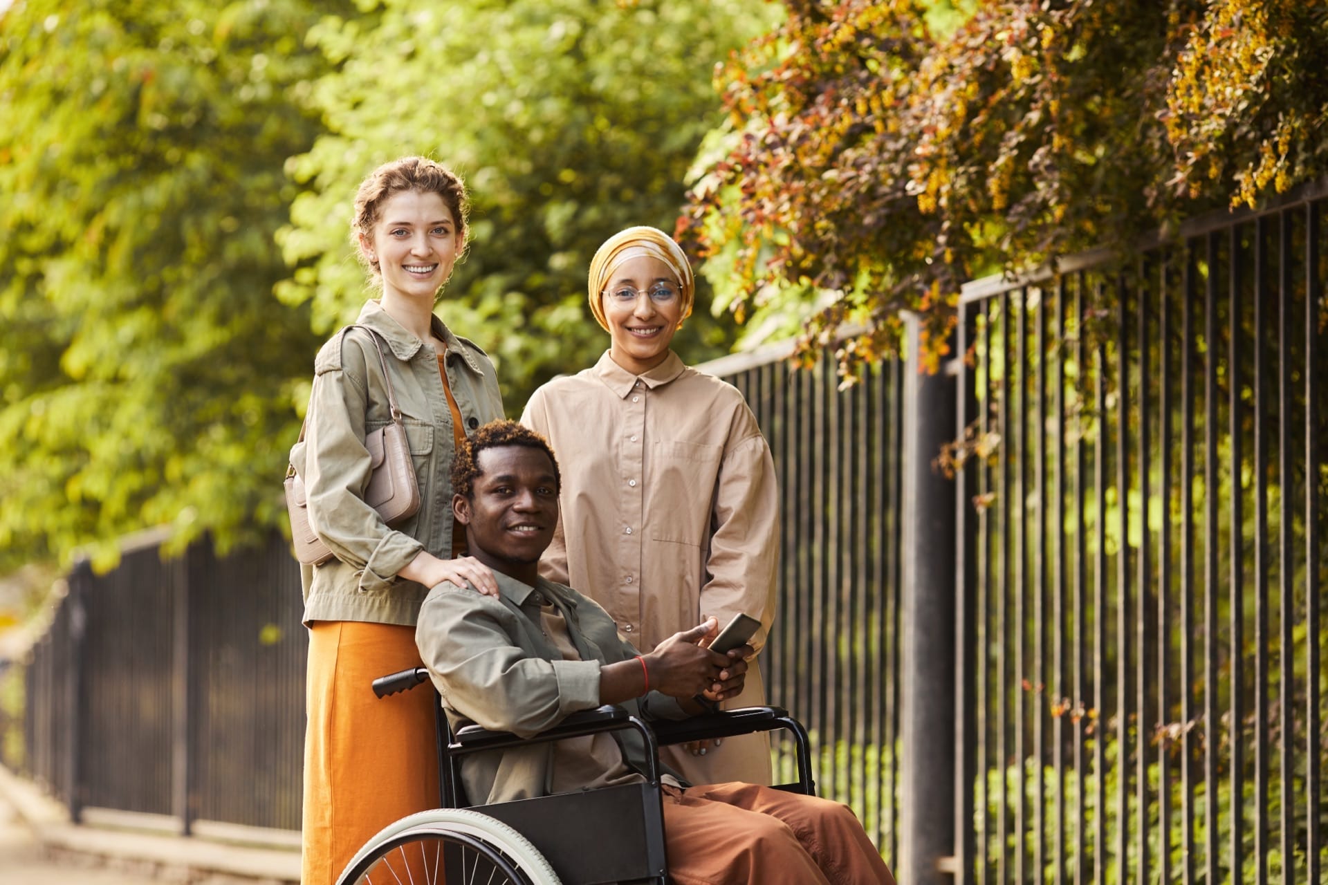 Trois jeunes adultes sourient ensemble en plein air – diversité, amitié et communauté